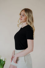 Load image into Gallery viewer, side view of model wearing the take a chance bodysuit in the color black. model has the top paired with the parker shorts and the dainty mallory necklace.