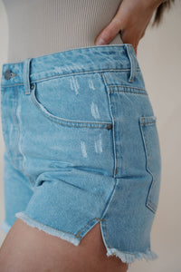 side detail view of model wearing the boston denim shorts. model has the shorts paired with the used to know bodysuit in the color biscuit.