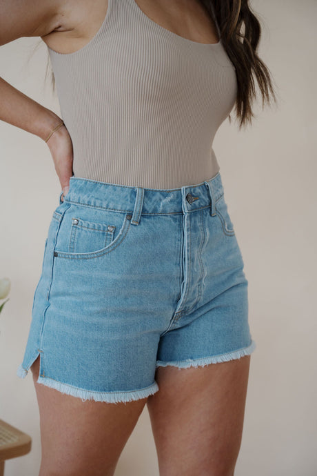 side view of model wearing the boston denim shorts. model has the shorts paired with the used to know bodysuit in the color biscuit.