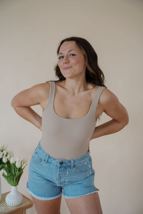 front view of model wearing the used to know bodysuit in the color biscuit. model has the top paired with the boston denim shorts and the anna necklace.