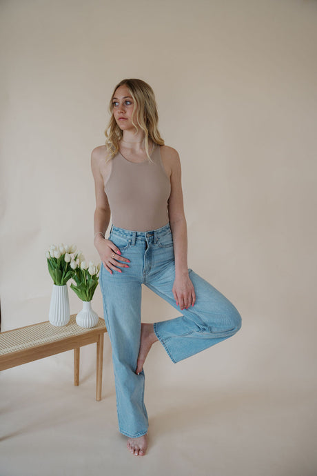 front view of model wearing the genevive denim. model has the denim paired with the change your mind bodysuit in the color light sand and the dainty mallory necklace.