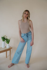 front view of model wearing the genevive denim. model has the denim paired with the change your mind bodysuit in the color light sand and the dainty mallory necklace.