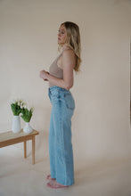 Load image into Gallery viewer, side view of model wearing the genevive denim. model has the denim paired with the change your mind bodysuit in the color light sand and the dainty mallory necklace.