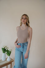 Load image into Gallery viewer, front view of model wearing the change your mind bodysuit in the color light sand. model has the top paired with the genevieve denim and the dainty mallory necklace.