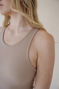 close front view of model wearing the change your mind bodysuit in the color light sand. model has the top paired with the genevieve denim and the dainty mallory necklace.