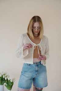 front view of model wearing the ocean avenue cardigan in the color cream. model has the cardigan paired with the forever yours top in the color macchiato and the austin denim shorts.