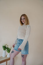 Load image into Gallery viewer, side view of model wearing the ocean avenue cardigan in the color cream. model has the cardigan paired with the forever yours top in the color macchiato and the austin denim shorts.