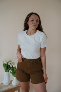 front view of model wearing the take a chance bodysuit in the color off white. model has the top paired with the hayden shorts and the anna necklace.