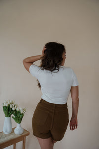 back view of model wearing the take a chance bodysuit in the color off white. model has the top paired with the hayden shorts and the anna necklace.