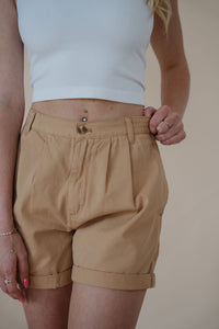 front detail view of model wearing the sweetest melody shorts in the color khaki. model has the shorts paired with the last to know top in the color white.