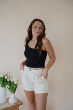 Load image into Gallery viewer, front view of model wearing the sweetest melody shorts in the color cream. model has the shorts paired with the last to know top in the color black.