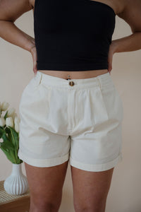 front detail view of model wearing the sweetest melody shorts in the color cream. model has the shorts paired with the last to know top in the color black.