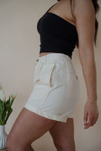 Load image into Gallery viewer, side detail view of model wearing the sweetest melody shorts in the color cream. model has the shorts paired with the last to know top in the color black.