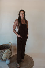 Load image into Gallery viewer, front view of model wearing the settlin&#39; down corduroy overalls in the color brown. model has the overalls paired with the here to stay top in the color brown.