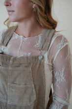 Load image into Gallery viewer, detail view of model wearing the settlin&#39; down corduroy overalls in the color taupe. model has the overalls paired with the here to stay top in the color cream.