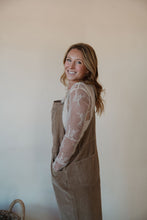 Load image into Gallery viewer, side view of model wearing the settlin&#39; down corduroy overalls in the color taupe. model has the overalls paired with the here to stay top in the color cream.