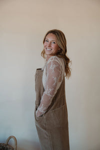 side view of model wearing the settlin' down corduroy overalls in the color taupe. model has the overalls paired with the here to stay top in the color cream.