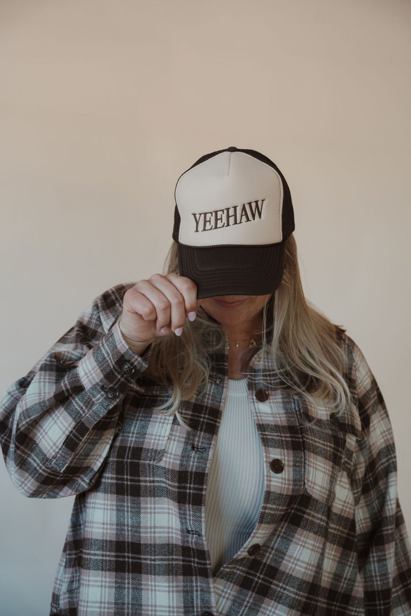 front view of model wearing the yeehaw trucker hat. model has the hat paired with the something's changed shacket and the forever yours tank in the color light beige.