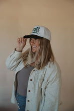 Load image into Gallery viewer, side view of model wearing the country and western trucker hat. model has the hat paired with the never be the same shacket and the change your mind bodysuit in the color smoky taupe.