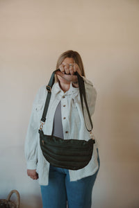 front view of model holding the it girl crossbody in the color olive. model has the bag paired with the never be the same shacket and the change your mind bodysuit in the color smoky taupe.