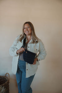 front view of model wearing the it girl crossbody in the color navy. model has the bag paired with the never be the same shacket and the change your mind bodysuit in the color smoky taupe.