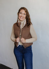 Load image into Gallery viewer, model wearing the vest of both worlds puffer in the color brown/cream. model has the vest paired with the can&#39;t get enough top in the color oatmeal and a pair of dark wash denim.
