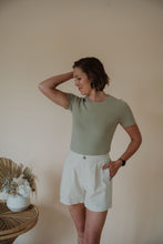 Load image into Gallery viewer, front view of model wearing the take a chance bodysuit in the color soft olive. model has the bodysuit paired with the making promises shorts.