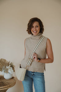 model wearing the weekend getaway bag in the color cream. model has the adjustable crossbody strap attached.
