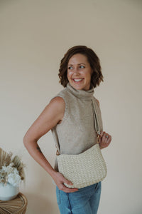 model wearing the weekend getaway bag in the color cream. model has the bag paired with the adjustable crossbody strap.