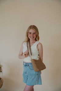 model wearing the weekend getaway bag in the color tan. model has the adjustable crossbody strap attached.