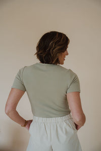 back view of model wearing the take a chance bodysuit in the color soft olive. model has the bodysuit paired with the making promises shorts.