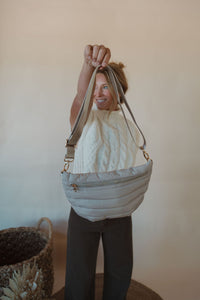 front view of model holding the it girl crossbody in the color sand. model has the bag paired with the all we knew sweater and the addison denim in the color brown.