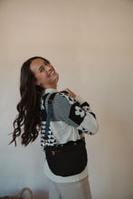 Load image into Gallery viewer, side view of model wearing the it girl crossbody in the color black. model has the bag paired with the where you are sweater and the siena denim.