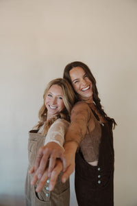 side view of models wearing the settlin' down corduroy overalls. models have the overalls paired with the here to stay top.