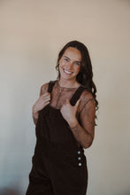 Load image into Gallery viewer, front view of model wearing the settlin&#39; down corduroy overalls in the color brown. model has the overalls paired with the here to stay top in the color brown.