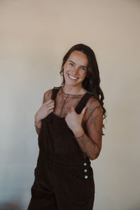 front view of model wearing the settlin' down corduroy overalls in the color brown. model has the overalls paired with the here to stay top in the color brown.