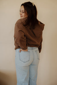 back view of model wearing the something more sweatshirt in the color chocolate. model has the sweatshirt paired with the camden denim.