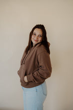 Load image into Gallery viewer, side view of model wearing the something more sweatshirt in the color chocolate. model has the sweatshirt paired with the camden denim.