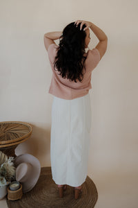 back view of model wearing the all over again denim midi skirt. model has the skirt paired with the nothing to prove top in the color dusty pink.