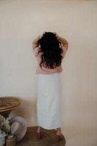 back view of model wearing the all over again denim midi skirt. model has the skirt paired with the nothing to prove top in the color dusty pink.