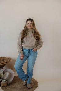 front view of model wearing the something more sweatshirt in the color taupe. model has the sweatshirt paired with the Hartford denim.