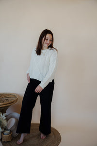 front view of model wearing the Addison denim in the color fade black. model has the denim paired with the somewhere in the middle sweater in the color white.