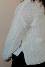 Load image into Gallery viewer, side view of model wearing the somewhere in the middle sweater in the color ivory. model has the sweater paired with the addison denim in the color fade black.
