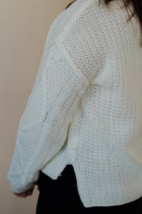 side view of model wearing the somewhere in the middle sweater in the color ivory. model has the sweater paired with the addison denim in the color fade black.