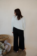 Load image into Gallery viewer, back view of model wearing the Addison denim in the color fade black. model has the denim paired with the somewhere in the middle sweater in the color white.