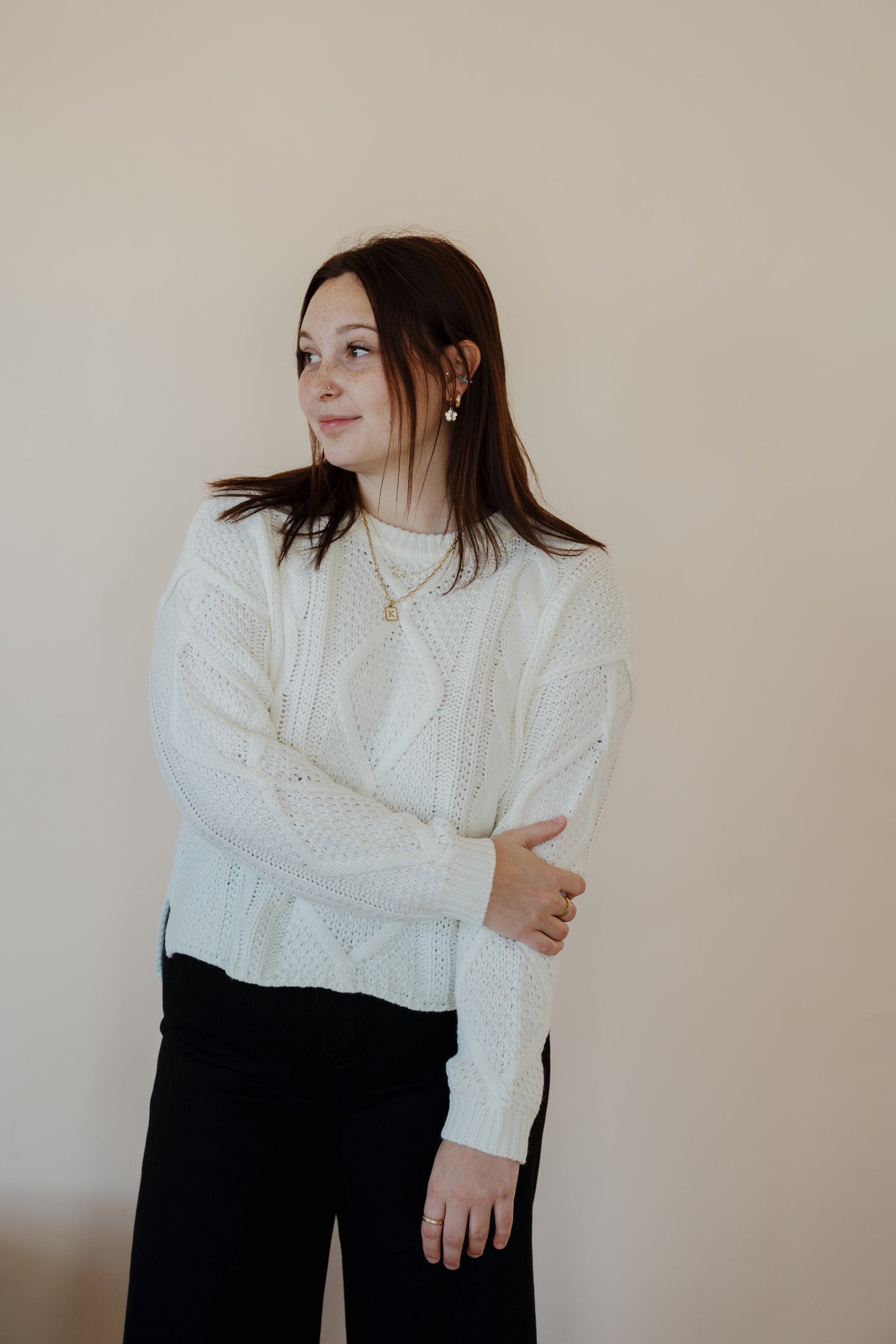 front view of model wearing the somewhere in the middle sweater in the color ivory. model has the sweater paired with the addison denim in the color fade black.