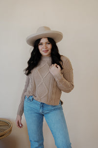 front view of model wearing the somewhere in the middle sweater in the color oat. model has the sweater paired with the Hartford denim.