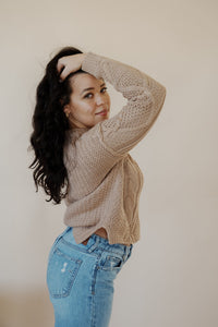 side view of model wearing the somewhere in the middle sweater in the color oat. model has the sweater paired with the Hartford denim.