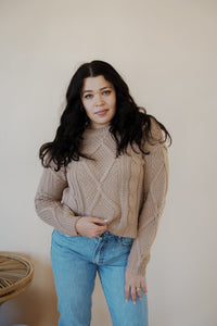 front view of model wearing the somewhere in the middle sweater in the color oat. model has the sweater paired with the Hartford denim.