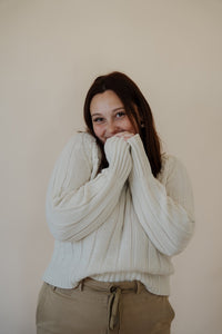 front view of model wearing the every moment sweater in the color ivory. model has the sweater paired with the in another life skirt.